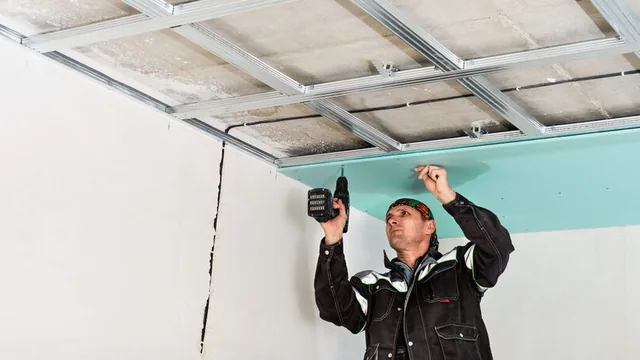 Instalador atornillando placa de pladur en un techo con aislamiento en una vivienda de Murcia